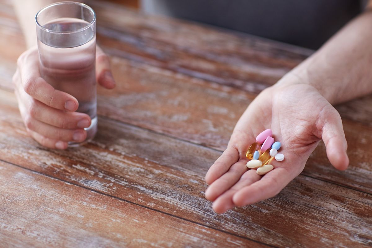 close up of male hands holding pills and water