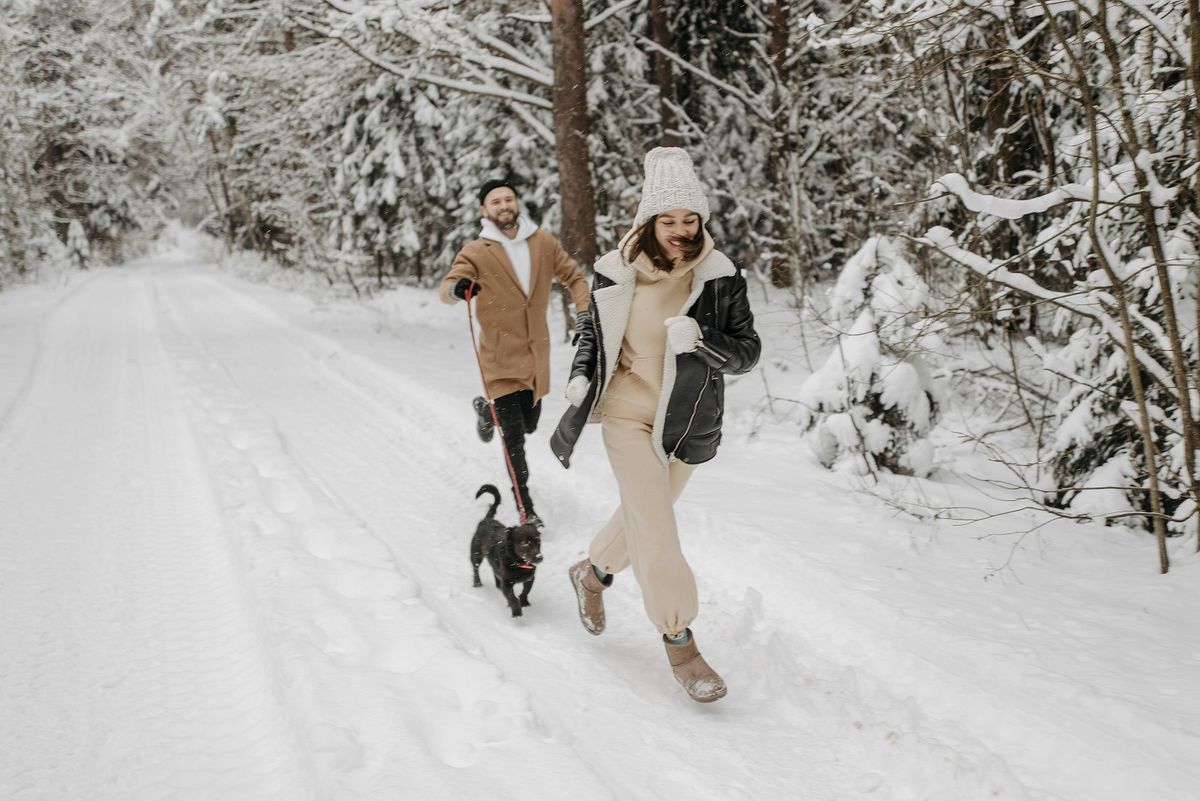 "Egy nő és egy férfi fut egy kutyával a havas erdőben