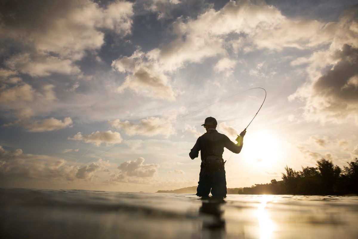 A man fly fishing in the ocean.