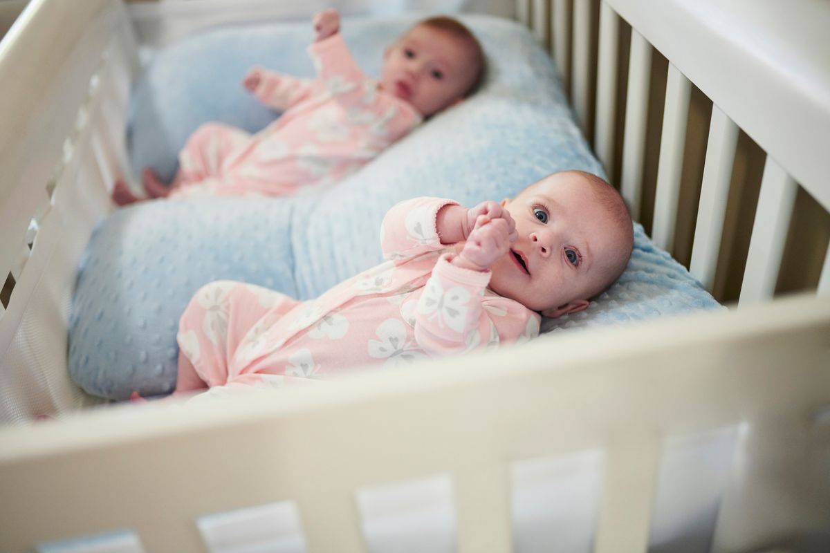 Twin baby girls lying in crib in nursery
ikrek