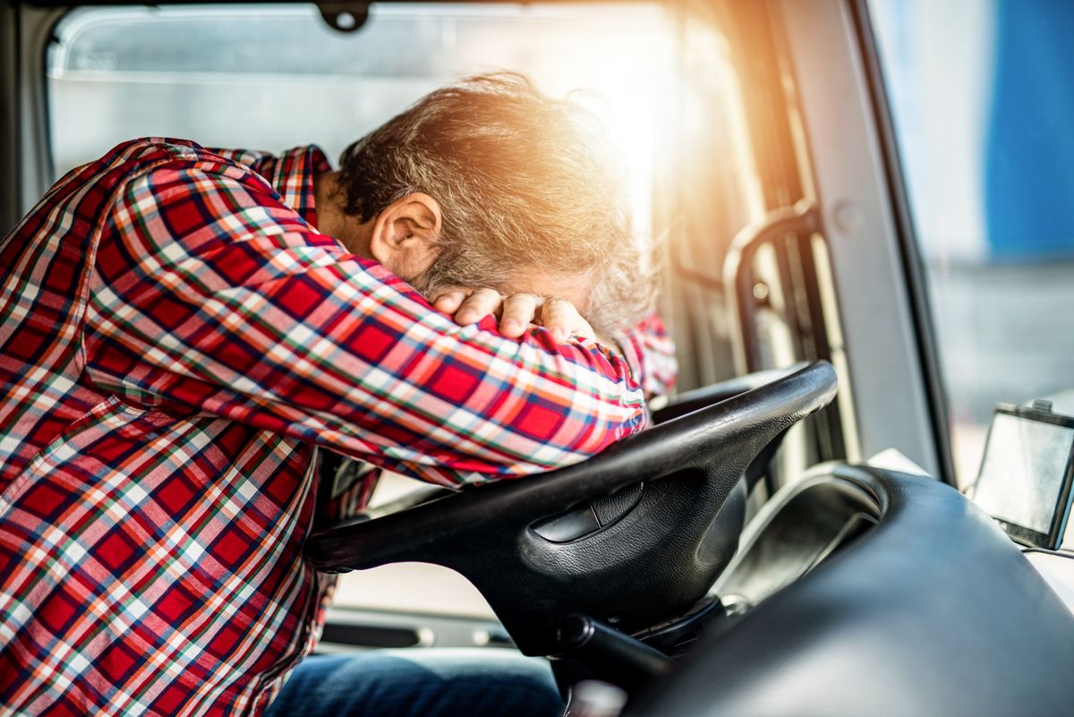 Tired mature truck driver sleeping on a truck steering wheel.
kamion