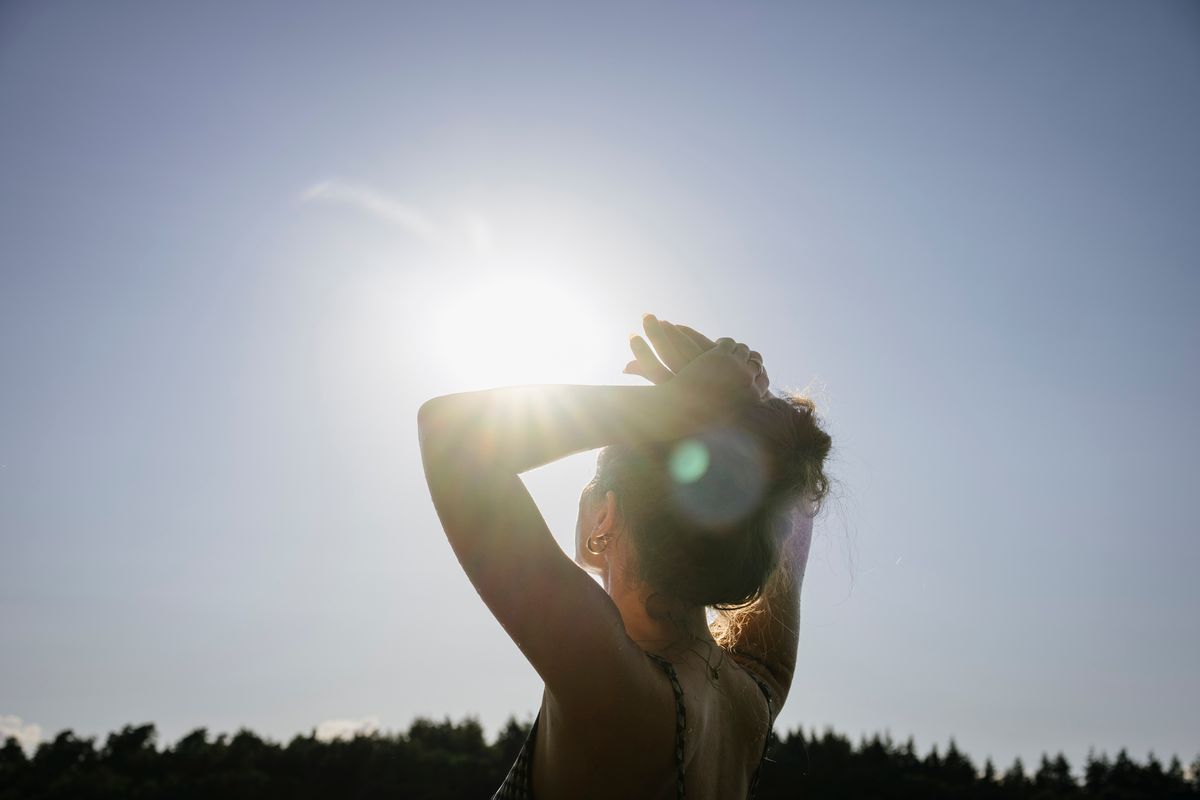 Sunlight shines into the camera while a woman looks up at the sky
időjárás