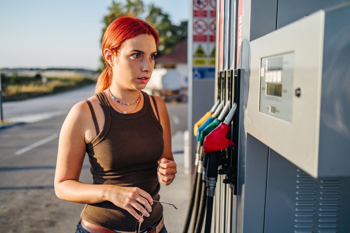 Shocked young woman looking at gas prices at a filling station
gázolaj