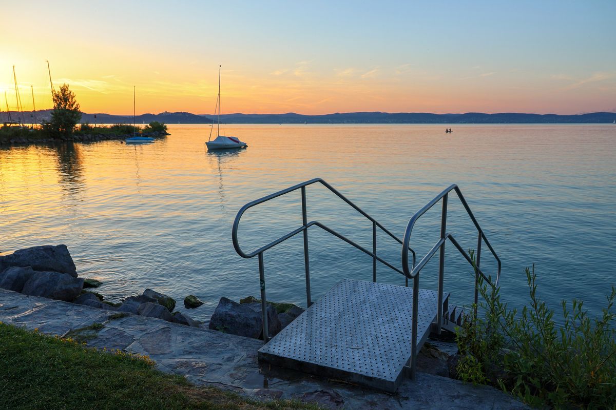 Lake Balaton pier stairs in sunset with sailboats
holttest